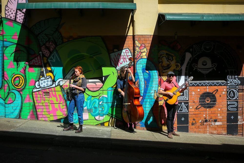 A busker band plays in front of colourful street art