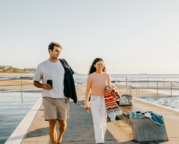 A young couple walking beside Merewether Baths