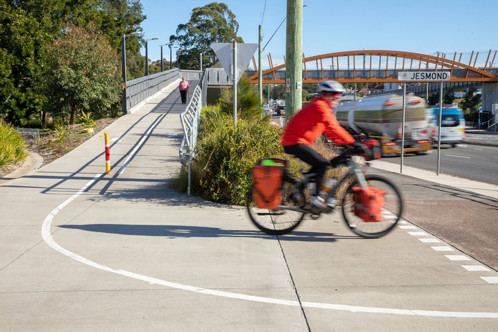 A person cycling in front of a road bridge