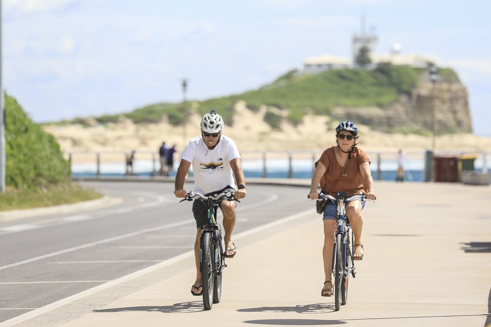 Two people riding bikes by the ocean