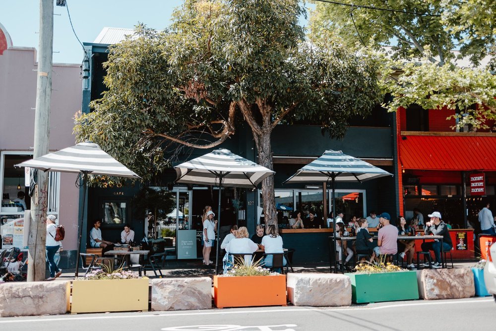 People dining on an outdoor deck under umbrellas on Darby Street