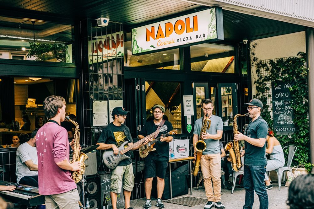 A band plays in the street in front of a popular restaurant