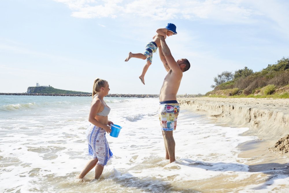 A family playing in the shallow water at Stockton Beach