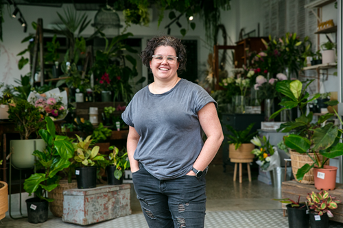 A business owner standing in front of her plant shop
