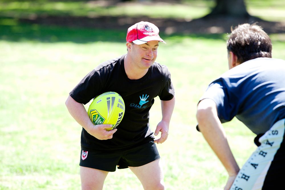 A young disabled man playing rugby with a friend
