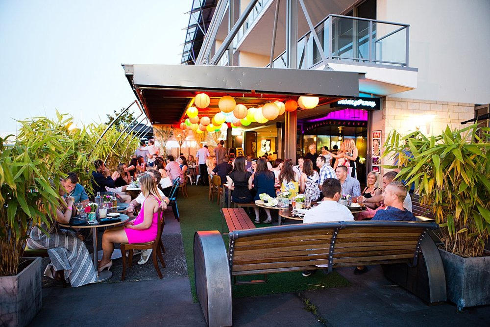 outdoor diners sitting under coloured balloons at dusk