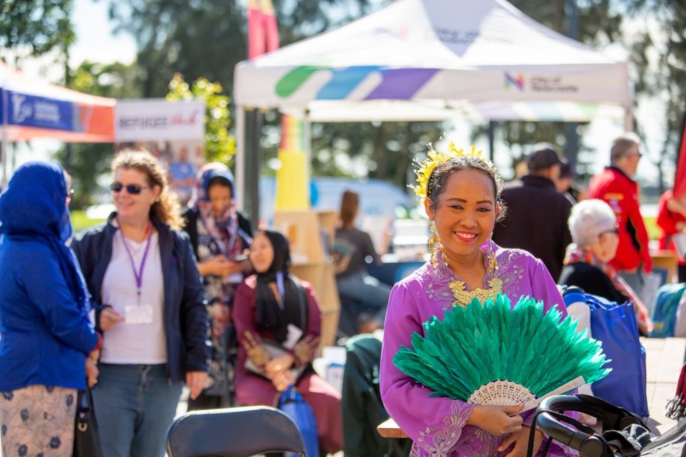 A lady at a cultural festival holding a green patterned fan