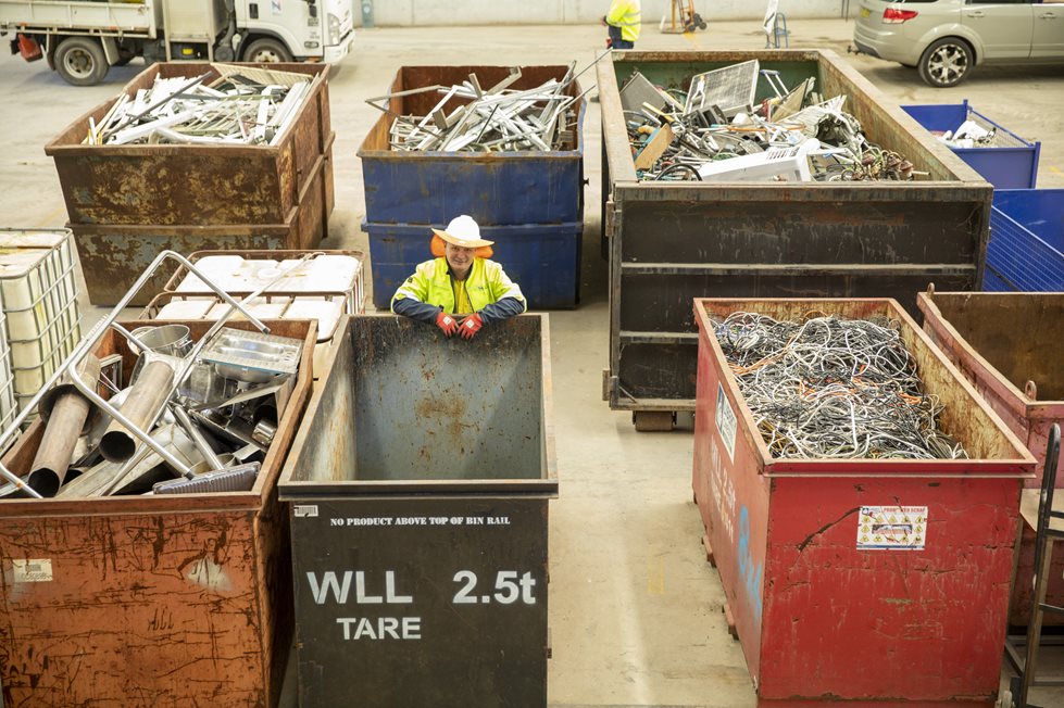 A council worker standing in between metal recycling bins
