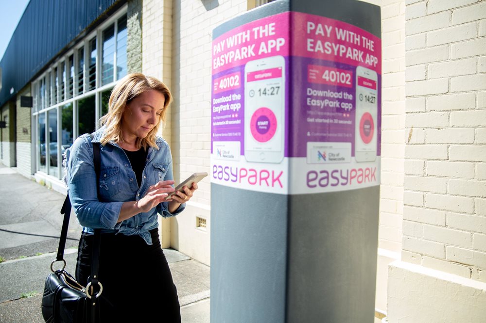 A woman using the Easy Park app in front a parking station