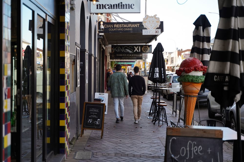 People walking on a footpath past restaurants on Beaumont Street, Hamilton
