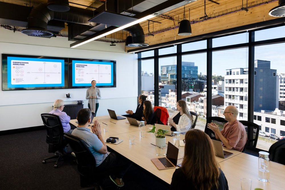 A woman presents to a board room with a view of the city