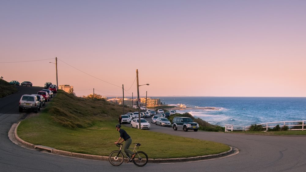 A man riding up a road near Newcastle beach at sunset