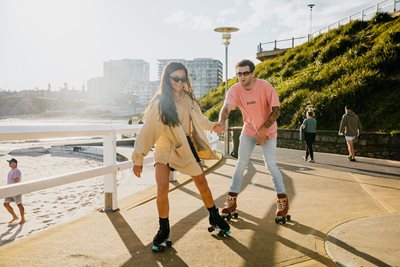 A couple roller skating on a path next to the beach