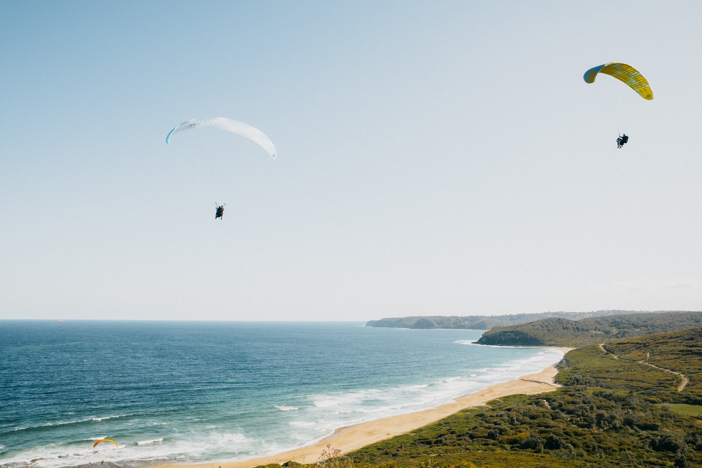 Two paragliders flying over the beach