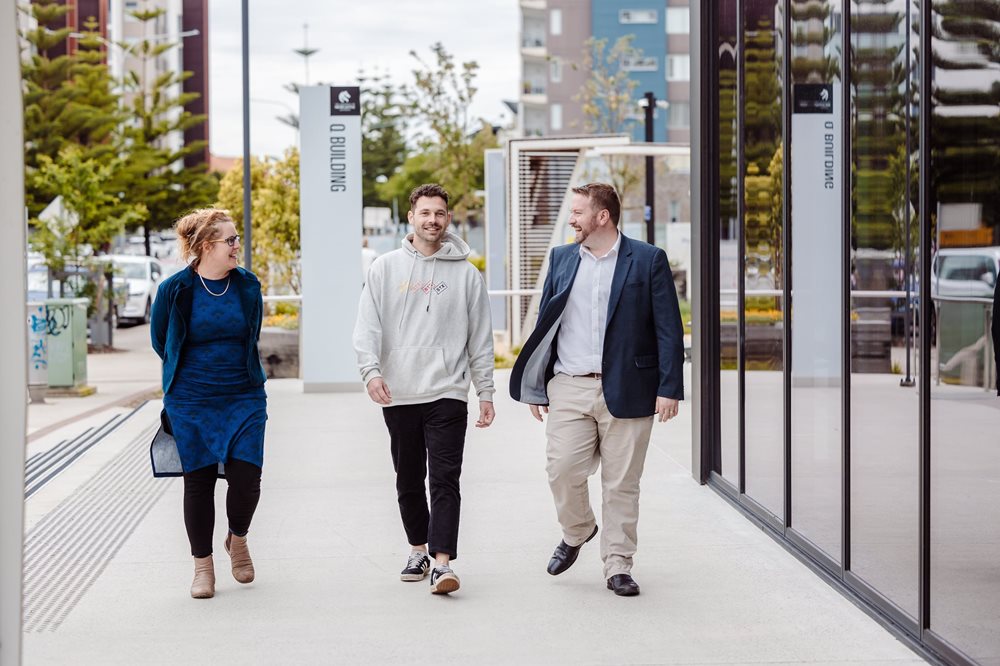 Three co workers of Astrolabe walking in front of the Landing Pad