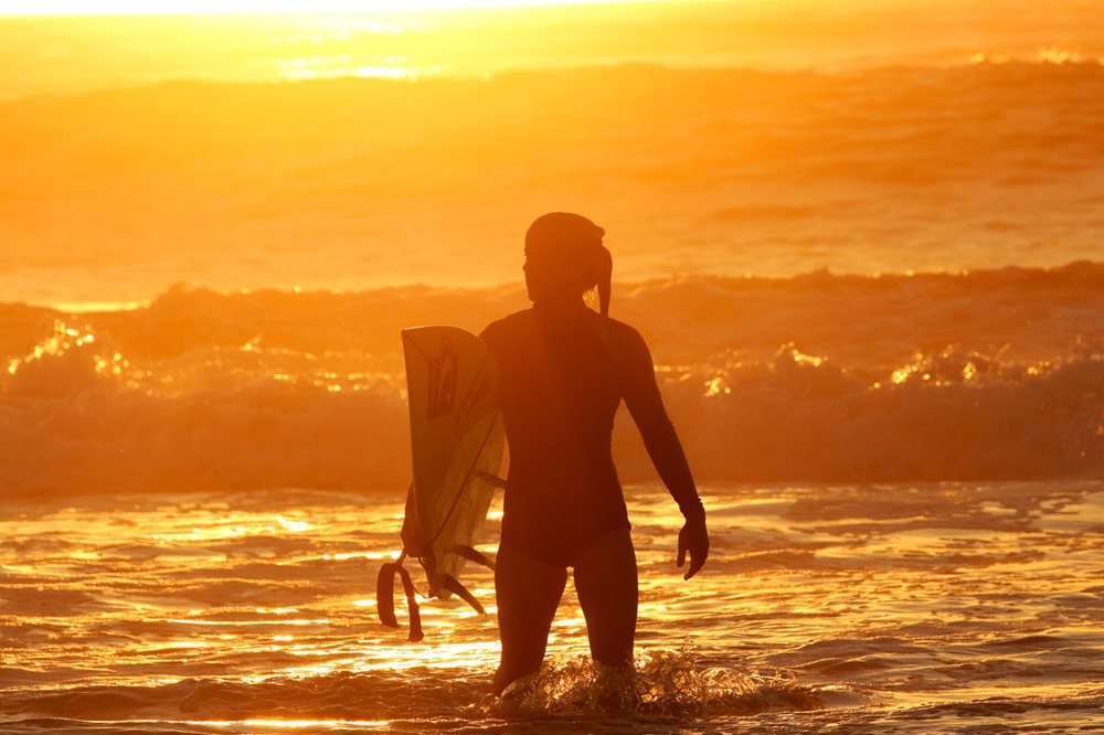 A girl walking into the surf at sunrise