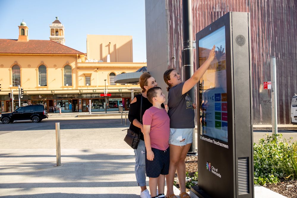 A woman and two kids using the digital screen near the Museum