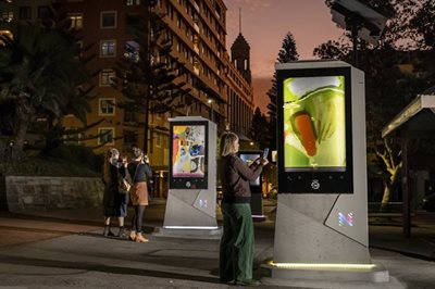 People activating digital art galleries with their phones at dusk