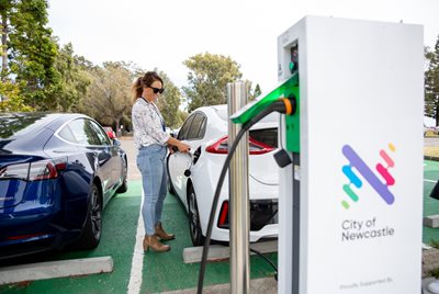 A woman charges her electric car at a charging station
