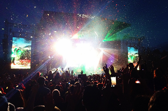 A festival at night with a crowd and lights on the stage